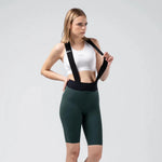 Woman wearing Gobik X Bib Short in dark green with white sports bra