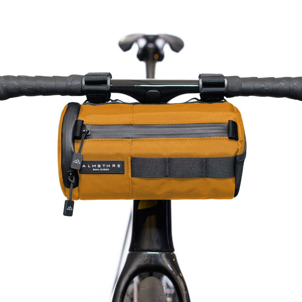 Orange ALMSTHRE handlebar bag mounted on bicycle handlebars with clean white background