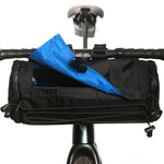 Black bicycle handlebar bag with blue umbrella attached, mounted on bike handlebars