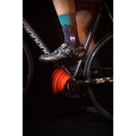 Cyclist wearing Taba Legg T cycling socks in teal and navy on Cannondale road bike