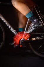 Cyclist wearing navy blue turquoise splatter cycling socks on Cannondale bike with spinning red chainring