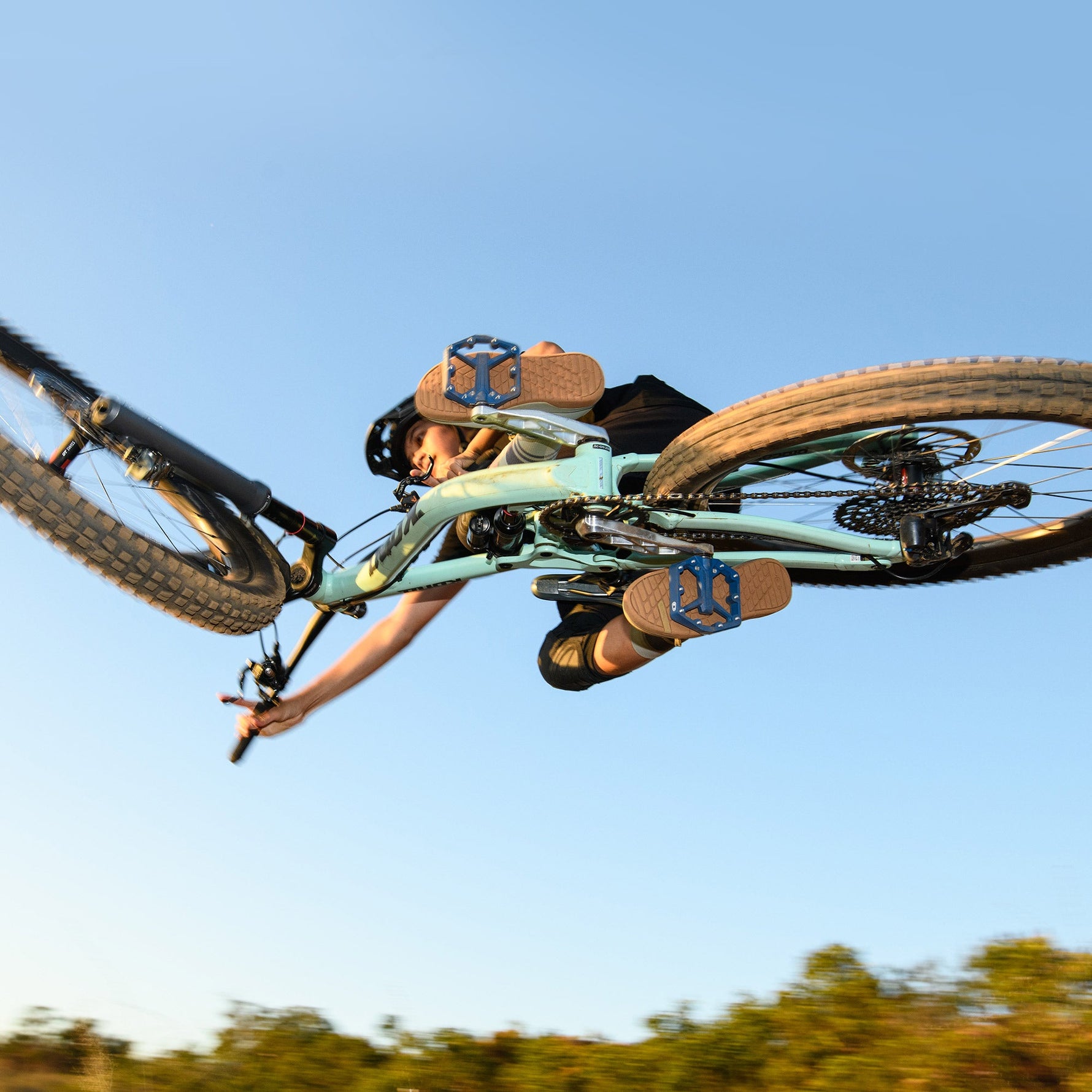 Crank Brothers Stamp 1 Small blue mountain bike pedals on rider's feet mid-air