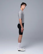 Male model wearing TheOneOff Krypton Short Sleeve Jersey Future Gray with black cycling shorts, side view