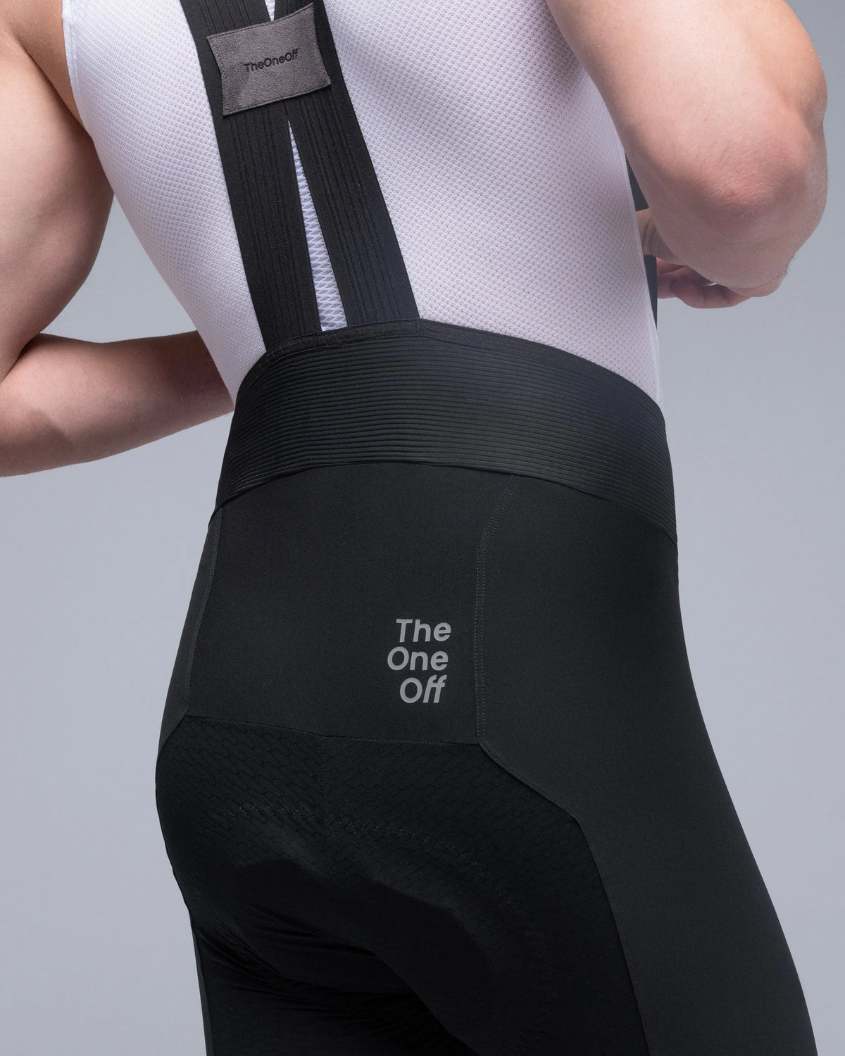 Close-up rear view of TheOneOff Xenon Bib Short in Future Black worn by male model