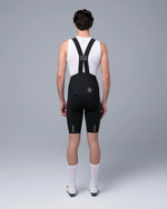 Male model wearing TheOneOff Xenon Bib Short in Future Black with white cycling base layer