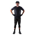 Male cyclist wearing Troy Lee Designs camo MTB shorts with knee pads and helmet