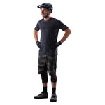Man wearing Troy Lee Designs Skyline cycling shorts in brushed camo military pattern with helmet and gloves