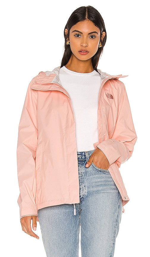 Woman wearing light pink North Face Venture 2 jacket with jeans on white background