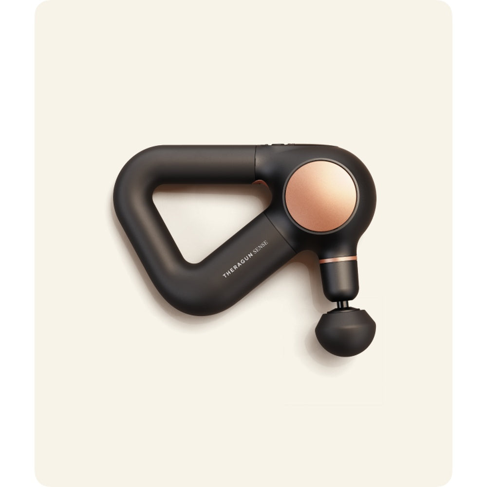 Therabody Theragun Sense percussion massager in black with rose gold details on cream background
