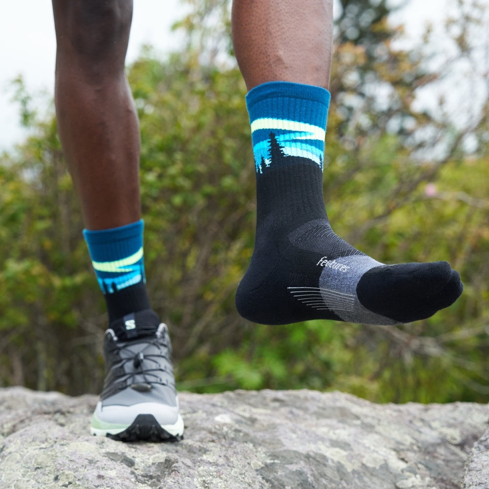 Feetures Trail Max Cushion Mini Crew socks in blue and charcoal worn outdoors