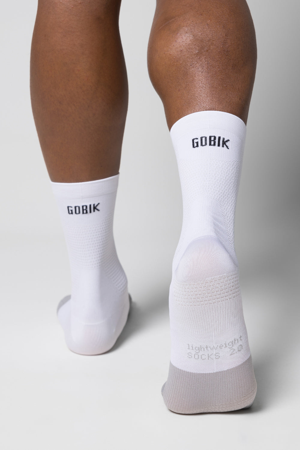 White GOBIK cycling socks worn on legs against clean studio background