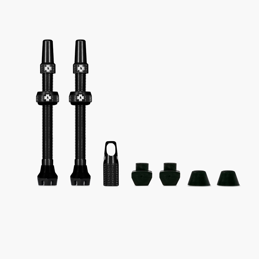 Muc-Off V2 Tubeless valve kit with black valves and green accessories on white background