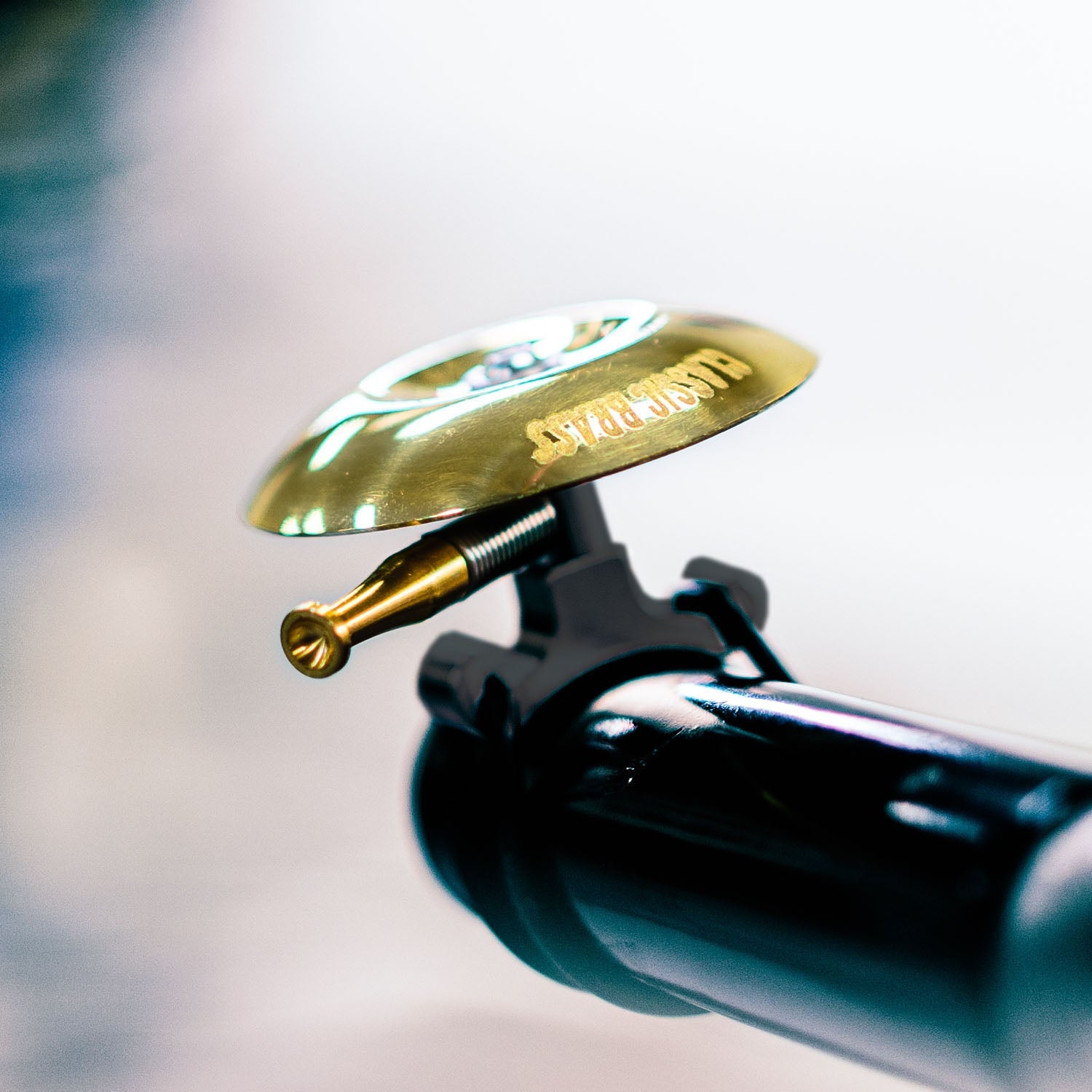 Lezyne Classic Shallow brass bicycle bell with black mounting hardware and threaded adjustment