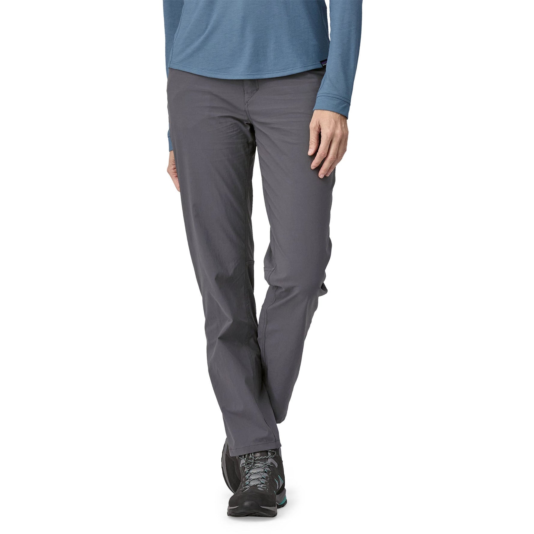 Woman wearing Patagonia grey Quandary pants with hiking boots on clean background