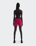 Back view of woman wearing On Performance 2/1 shorts in pink with black top