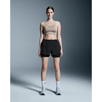 Woman wearing black On Performance 2-in-1 shorts with compression liner and sports bra