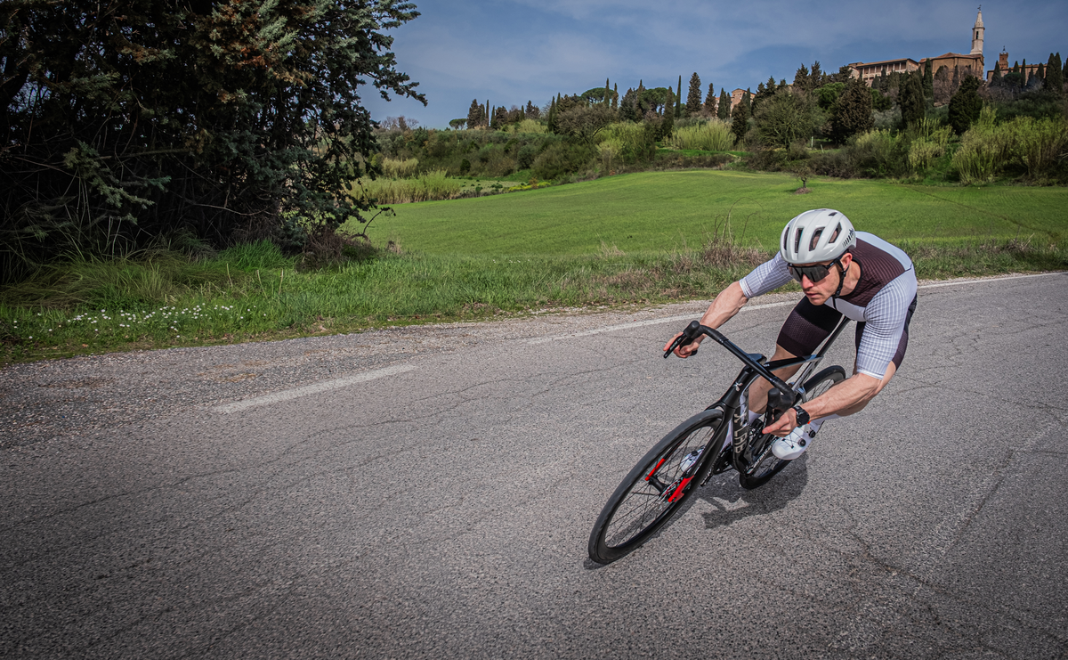 Cyclist riding X-LAB AD8 road bike on scenic Tuscan countryside road at speed