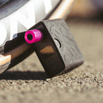 Muc-Off AirMach Mini Pro Electric Inflator in black with pink accent button on concrete