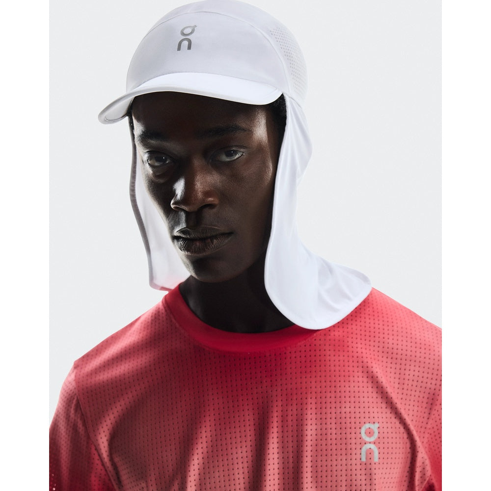 Model wearing white On Solar Cap with neck protection and red athletic shirt
