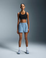 Woman wearing On 3 inch Core Shorts in chambray blue with black sports bra