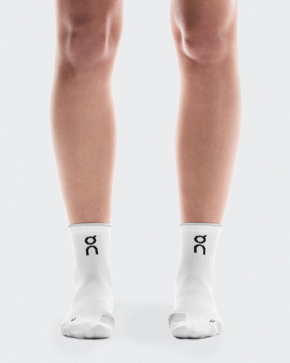 On Performance Run Sock Mid Unisex in white with glacier trim worn on model legs