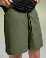 Man wearing olive green On Essential Shorts with drawstring waistband and side pockets