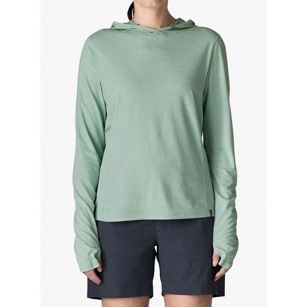 Woman wearing sage green Patagonia hooded long-sleeve shirt with dark shorts