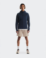 Man wearing On 7 inch Core Shorts in desert beige with navy jacket