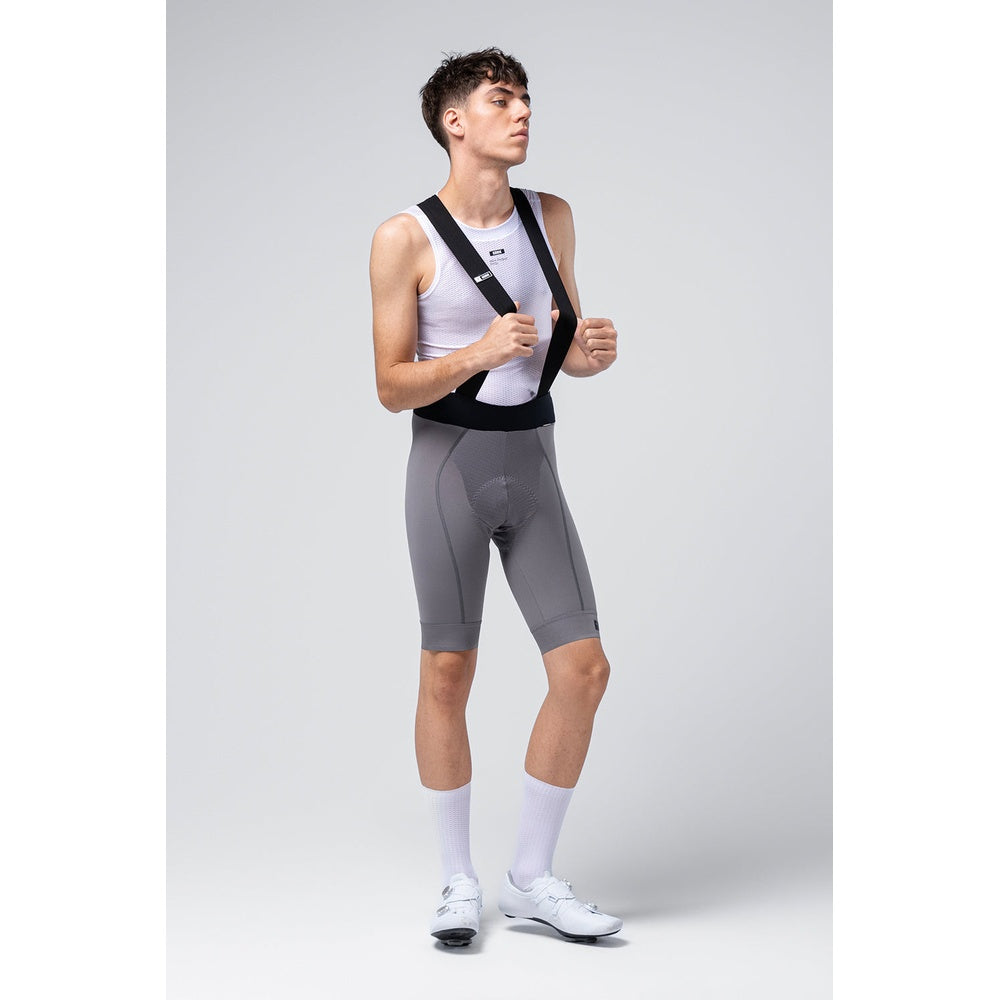 Male cyclist wearing Gobik Absolute 7.0 gray bib shorts with white base layer and cycling shoes