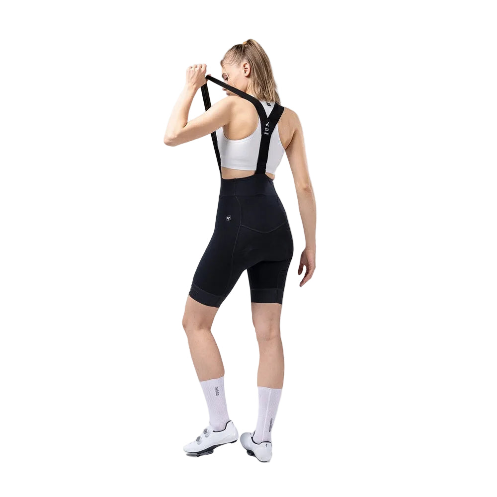 Woman wearing black GOBIK cycling bibshorts with suspenders in studio setting