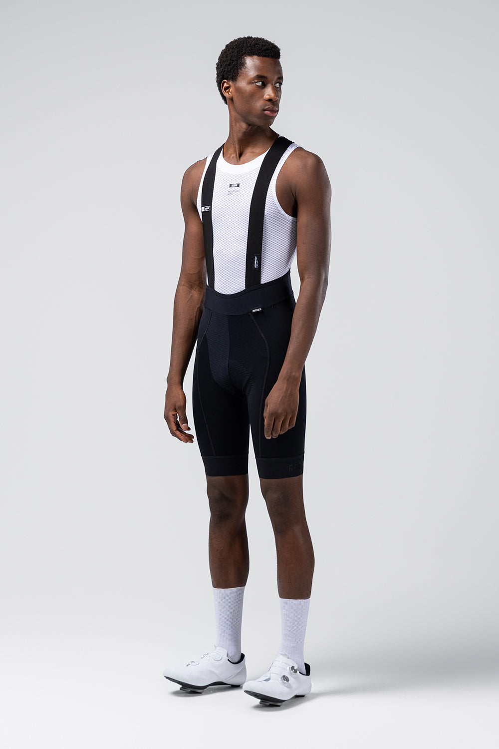 Male cyclist model wearing Gobik Absolute 7.0 black bib shorts with white base layer