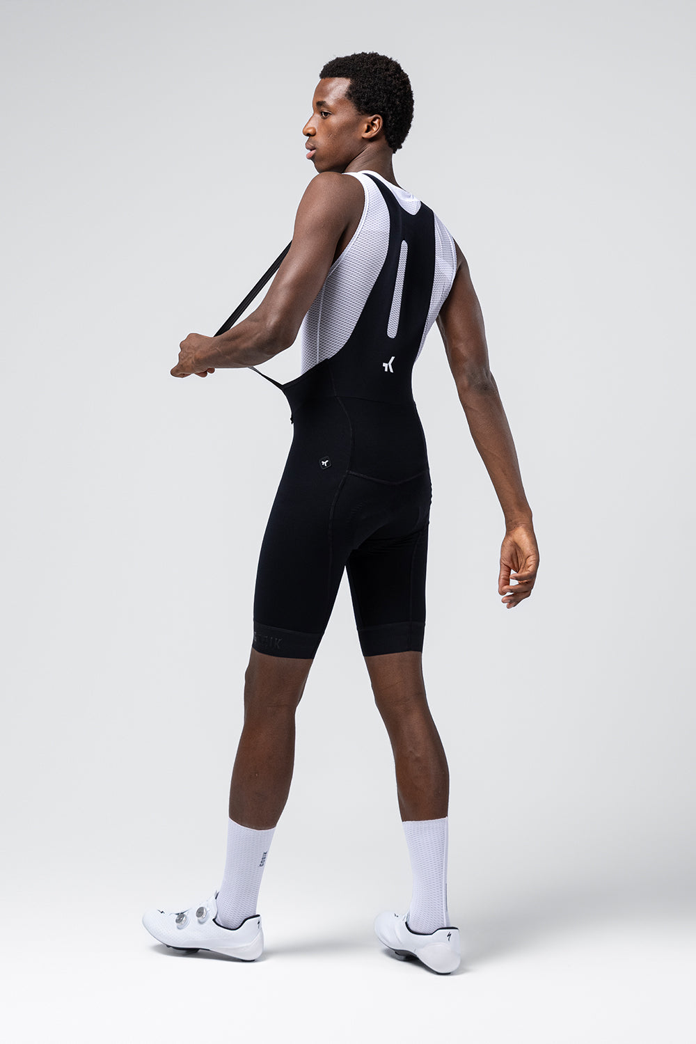 Male cyclist modeling Gobik Absolute 7.0 black bib shorts with white mesh straps