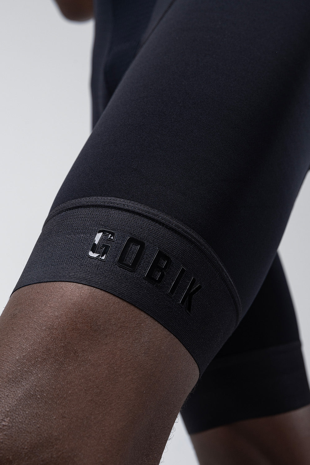 Close-up of black Gobik cycling bib shorts showing leg gripper with brand logo