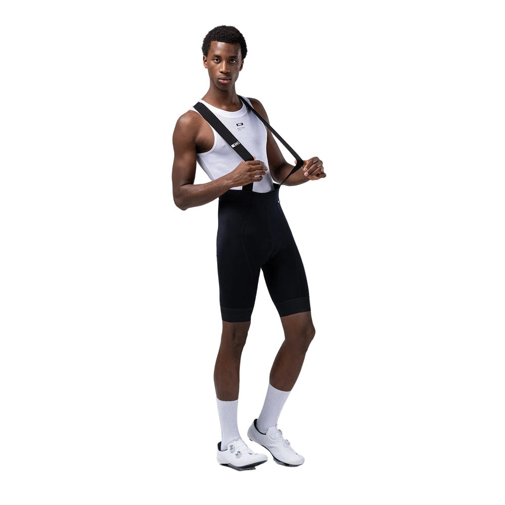 Male model wearing black Gobik cycling bib shorts with white tank top and cycling shoes