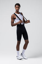 Male cyclist wearing Gobik Absolute 7.0 black bib shorts with white base layer and cycling shoes