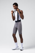 Male cyclist wearing gray Gobik Absolute Compact 7.0 bib shorts with white jersey