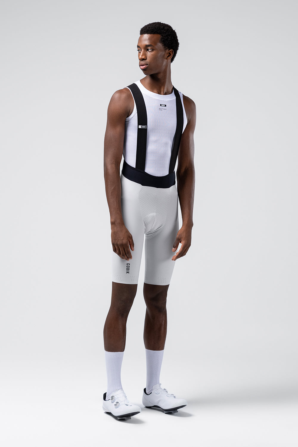 Male model wearing white Gobik Lancer bib shorts with black straps and mesh base layer