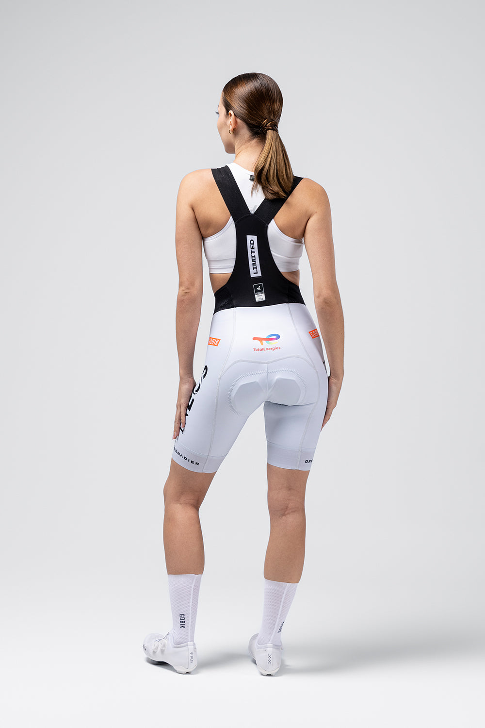 Woman wearing white Gobik Limited Print Bib Short with TotalEnergies Ineos Grenadiers team design