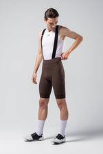 Male cyclist wearing dark brown Gobik Matt 2.0 bib shorts with white jersey