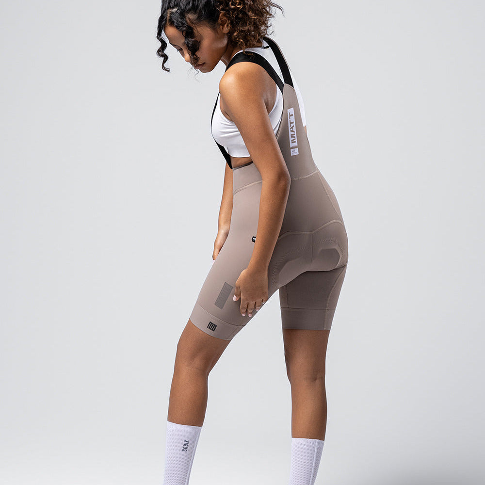 Woman wearing Gobik Matt 2.0 bib shorts in taupe color with white sports bra