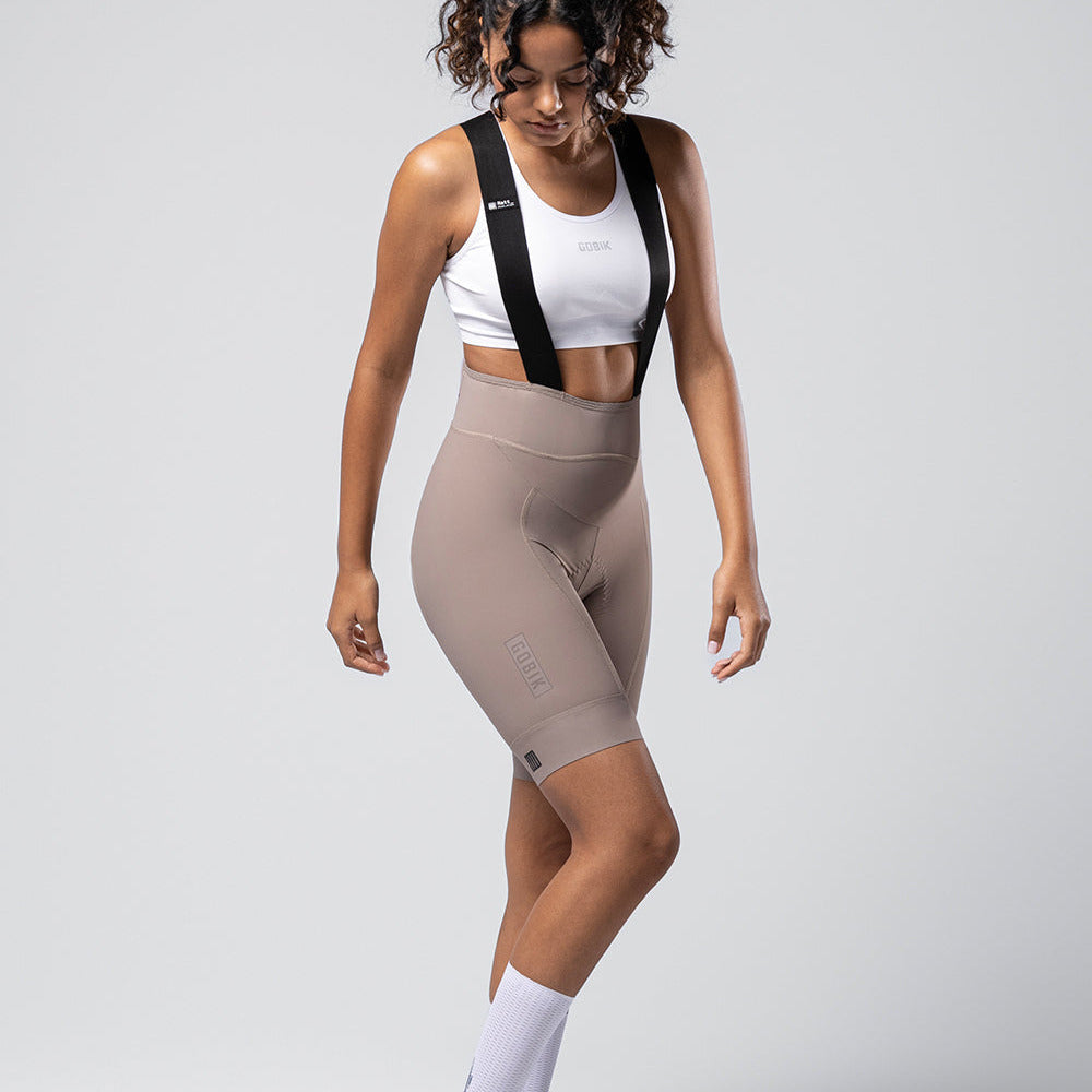 Woman wearing Gobik Matt 2.0 bib shorts in taupe with white sports bra