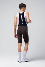 Rear view of male cyclist wearing black Gobik X bib shorts with white tank top