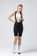 Woman wearing black Gobik X bib shorts with white sports bra and white socks
