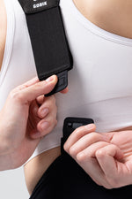 Woman adjusting black Gobik X bib shorts straps, showing buckle mechanism