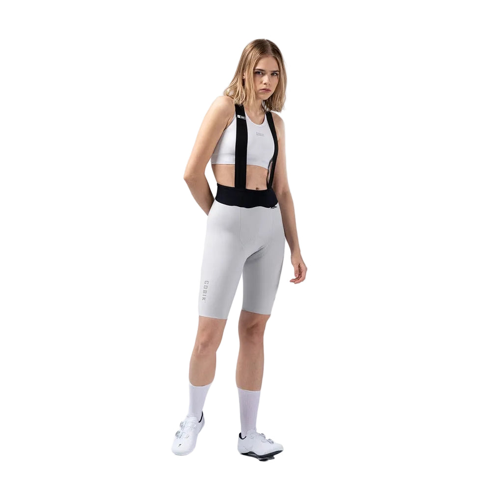 Woman wearing white Gobik X bib shorts with black straps in studio setting