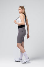 Woman wearing gray Gobik X Bib Short cycling shorts with white top and shoes