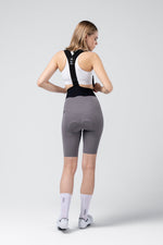 Woman wearing Gobik X Bib Short in gray/kettle color, rear view showing fit and design