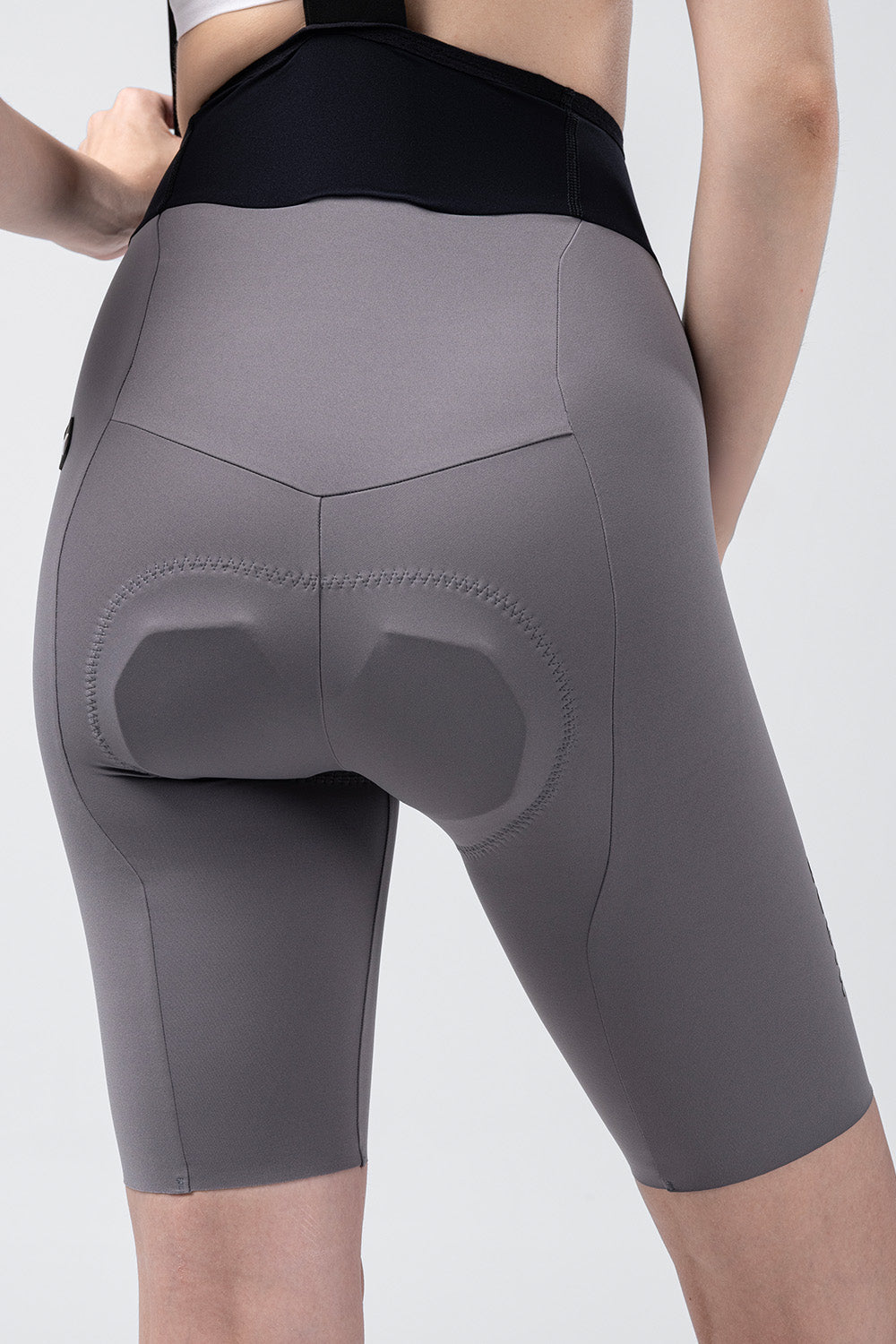 Women's gray cycling bib shorts with padded chamois, rear view on model
