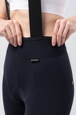 Woman wearing Gobik X navy blue cycling bib shorts with suspenders, rear view