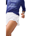 Woman wearing white Brooks Chaser 3-inch running shorts with blue long-sleeve top